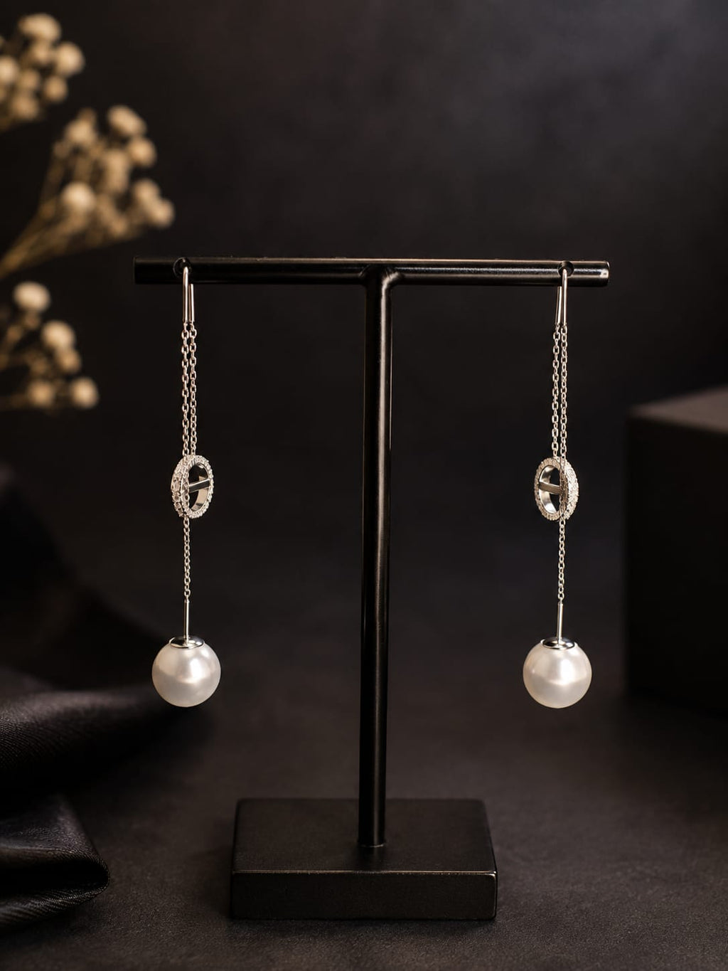 Boucles d'oreilles pendantes argentées perle et anneau strass - vue rapprochée sur présentoir noir