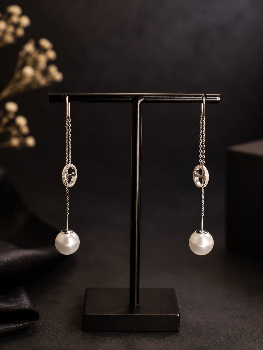 Boucles d'oreilles pendantes argentées perle et anneau strass - vue rapprochée sur présentoir noir
