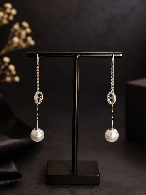 Boucles d'oreilles pendantes argentées perle et anneau strass - vue rapprochée sur présentoir noir