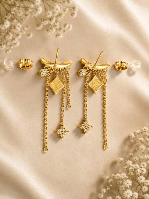 Boucles d'oreilles pendantes dorées étoiles strass - vue à plat sur satin